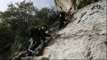 Homens subindo escada da 'Via Ferrata' - Getty Images